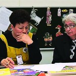 To kvinner sitter ved et bord og ser på noen papirer.