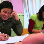 En ung mann sitter og skriver på et ark.