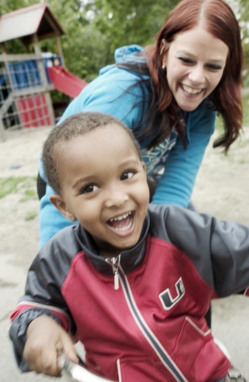 en liten gutt på sykkel og en dame som ler.