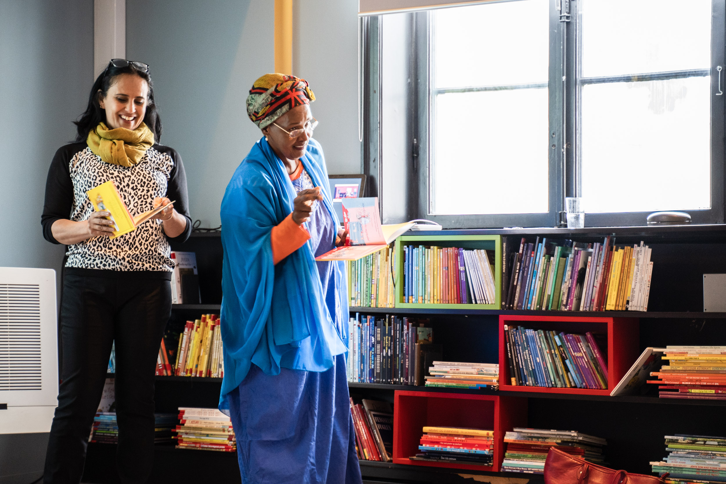 to damer står og leser høyt fra en bok