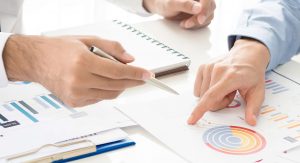 hender peker på diagrammer på et bord