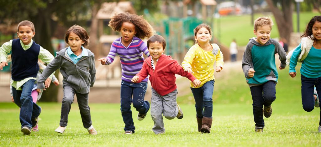 En rekke barn løper på gresset.