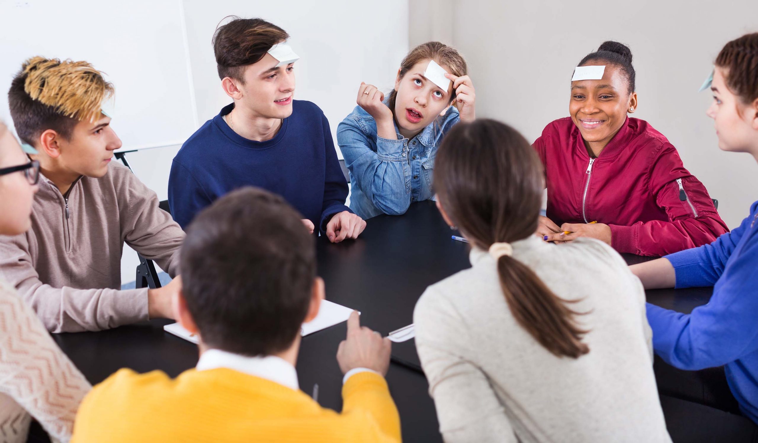 En gruppe ungdommer spiller et spill sammen. I panna har de hvite lapper.