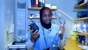 en kvinnelig helsearbeider holder fram et stetoskop og en toalettmappe