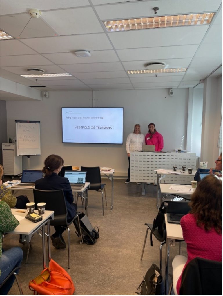 to kvinner står ved siden av en skjerm