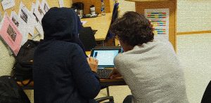 En morsmålsassistent hjelper en deltaker med en ipad i voksenopplæringen.