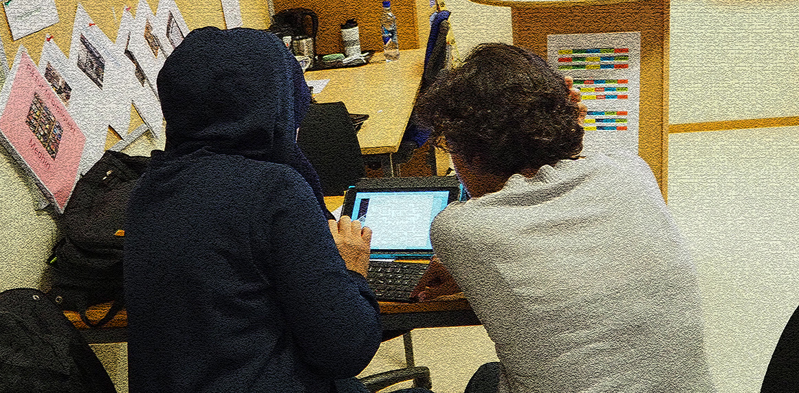 En morsmålsassistent hjelper en deltaker med en ipad i voksenopplæringen.