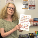 en kvinne med langt, krøllete hår viser fram en plakat med det ukrainske alfabetet