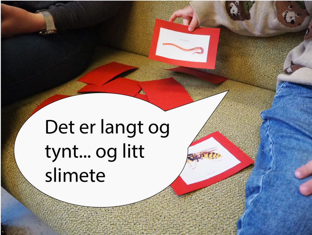 Foto av et barn som sitter i en sofa. Barnet holder et kort med bilde av en mark. I en snakkeboble står det: Det er langt og tynt, og litt slimete.