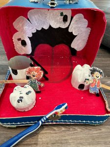 Eventyrkoffert med Karius og Baktus i en munn,