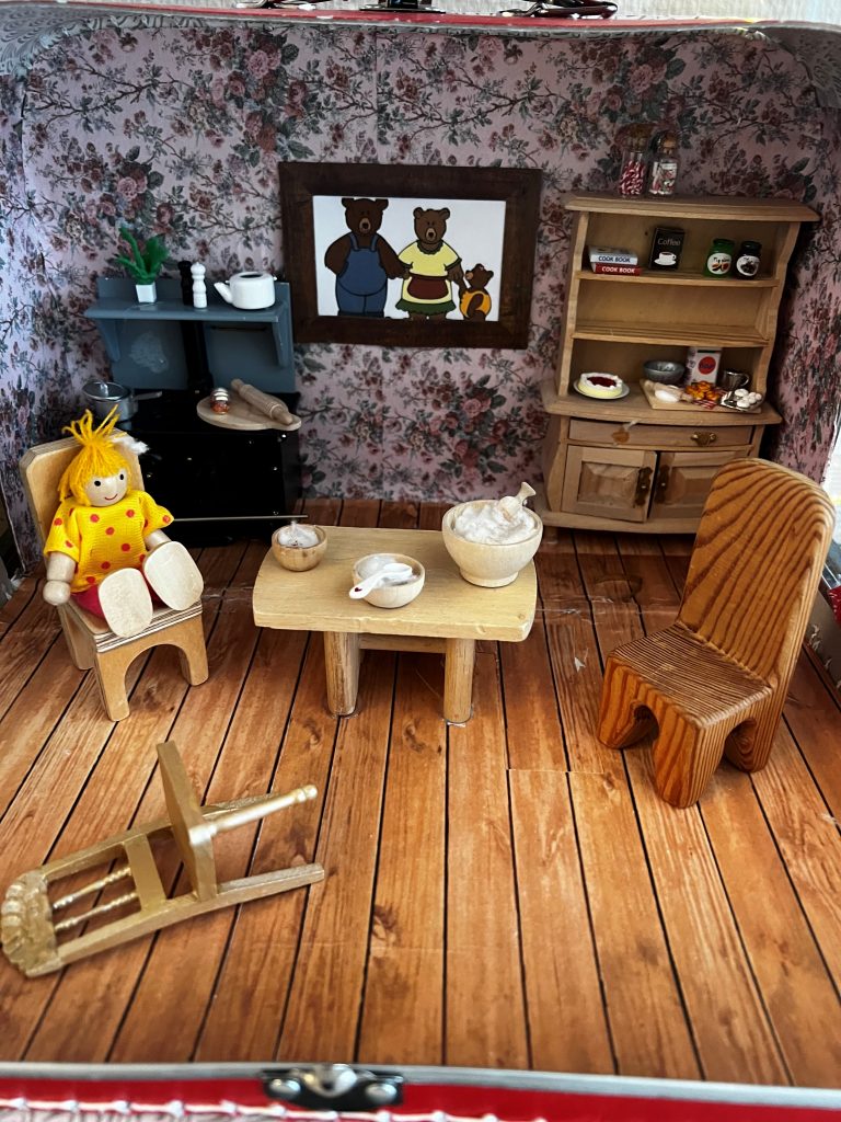 Foto av innholdet i eventyrkoffert med sitteplass i stue.