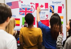 Foto av elever som henger opp flagg og ordet "hei" på flere språk på en tavle