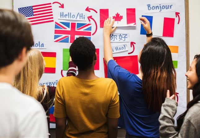Foto av elever som henger opp flagg og ordet "hei" på flere språk på en tavle