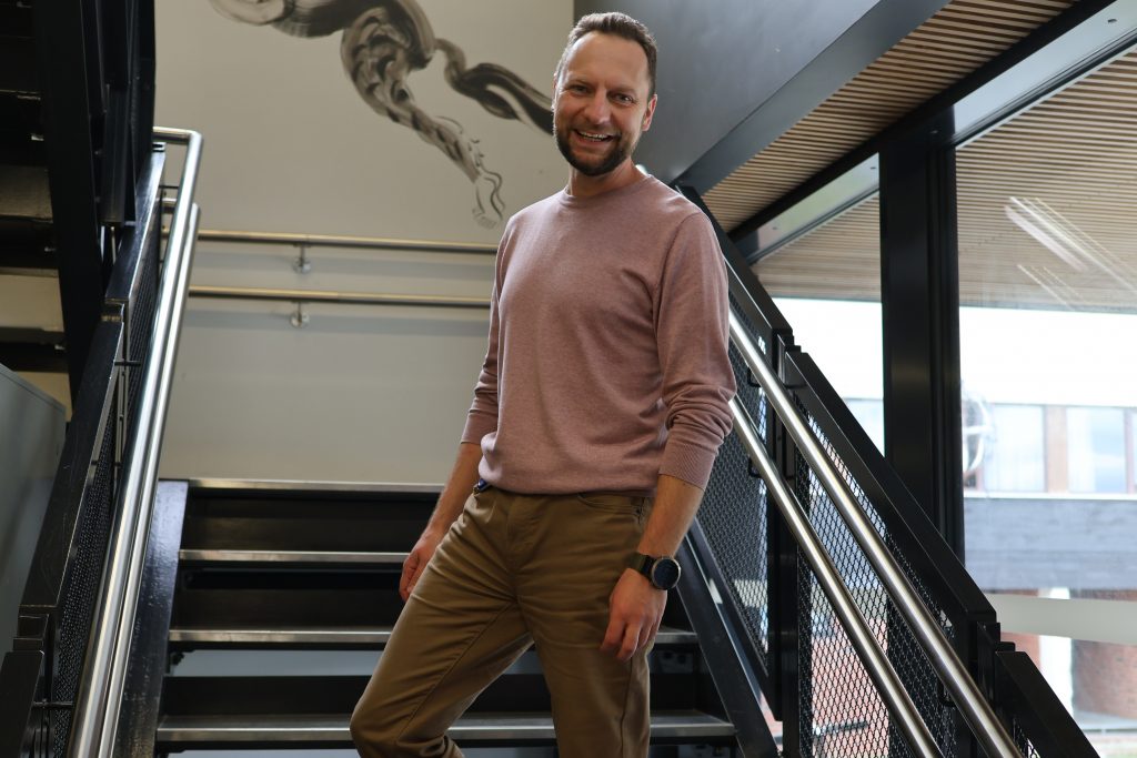 Fotografi av Andrii Minchenko. Han står i en trapp og smiler.